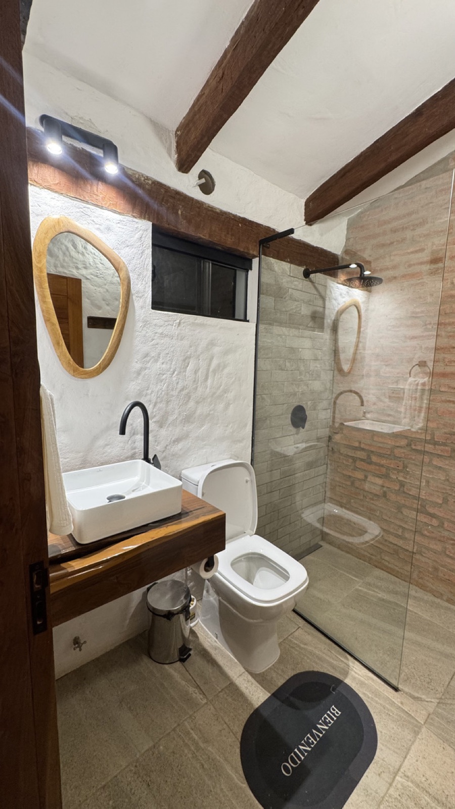 Baño completo con ducha de vidrio y lavamanos sobre mesada de madera