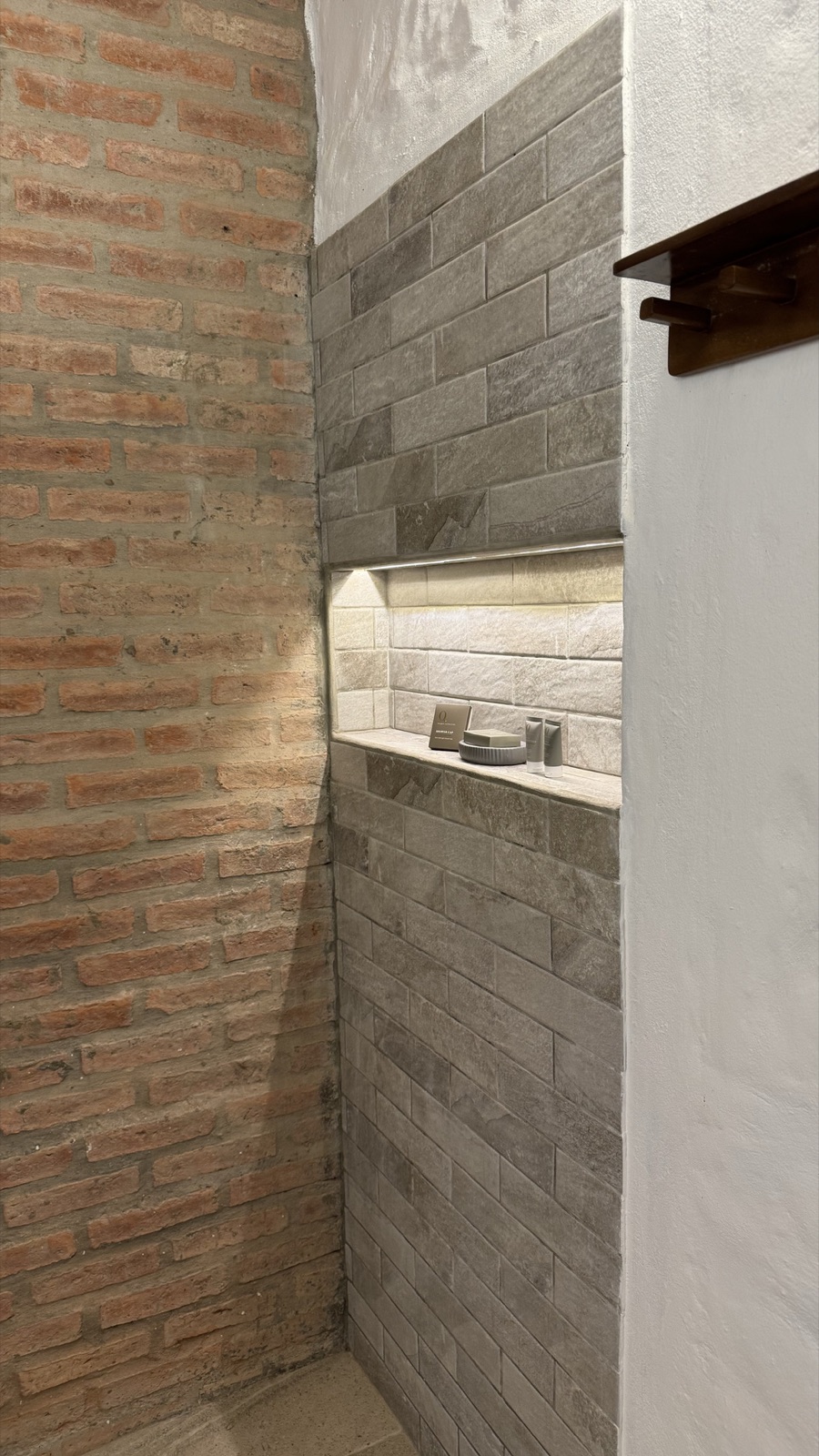 Ducha amplia con pared de ladrillo y cerámica tipo piedra