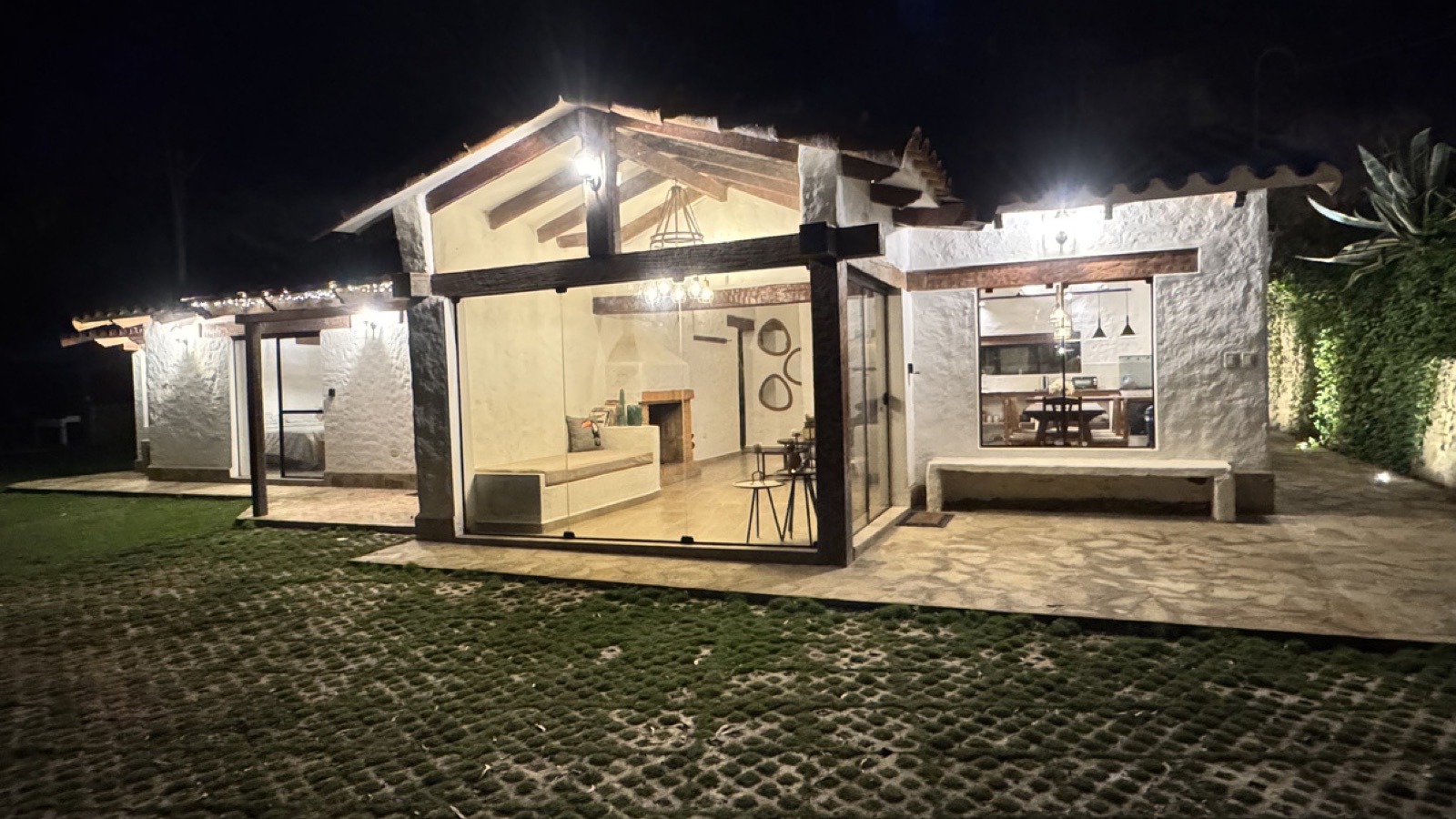Cabaña Erebor iluminada de noche, con la sala y el comedor visibles tras los ventanales