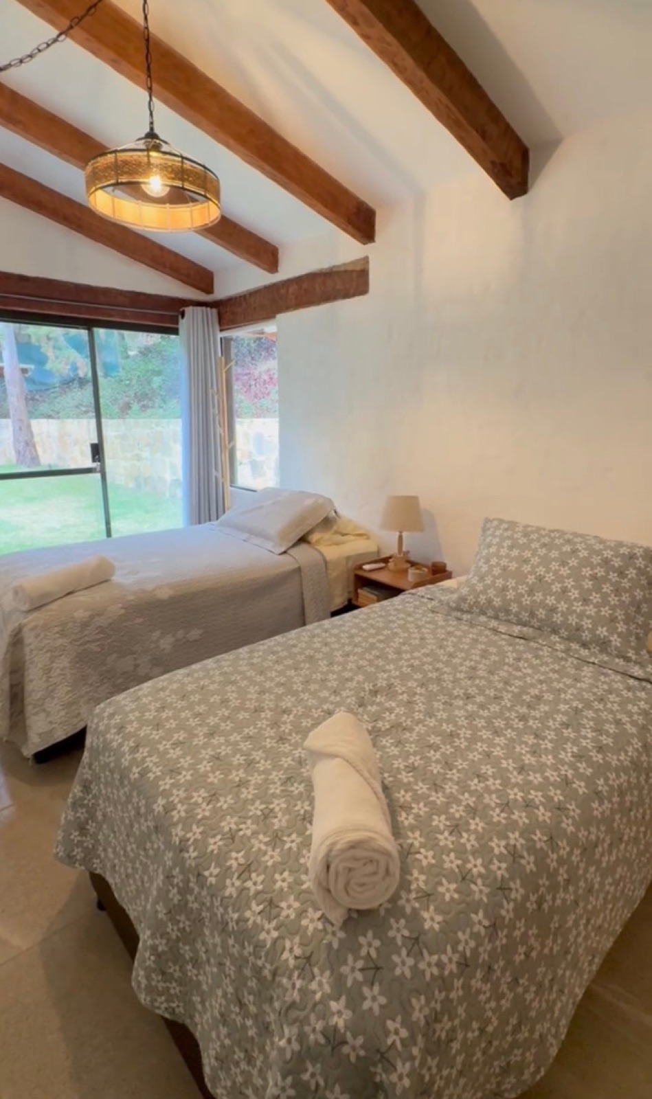Habitación con dos camas individuales y ventanal al jardín en Cabaña Erebor