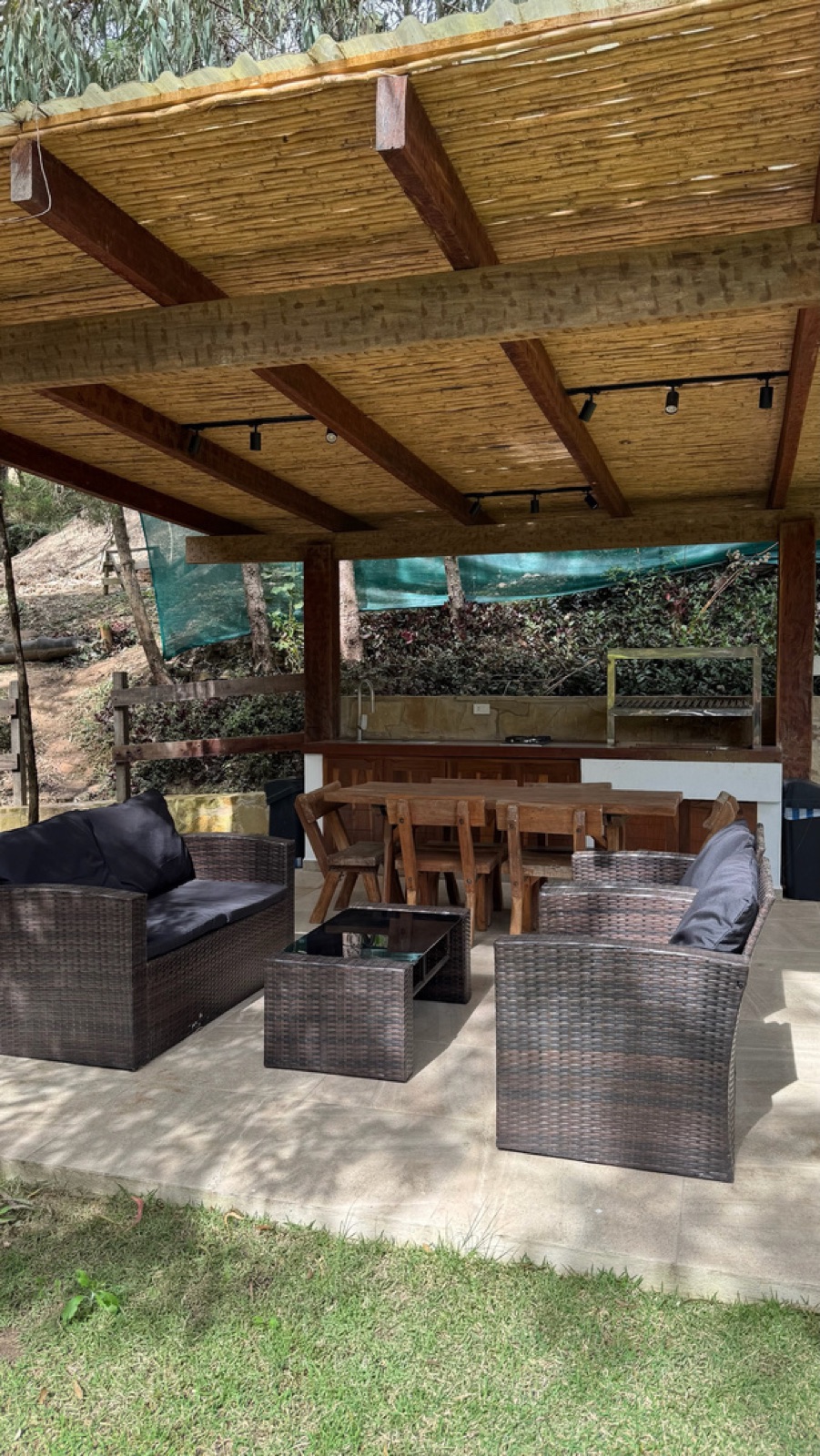 Quincho techado con sillones y mesa junto a la churrasquera
