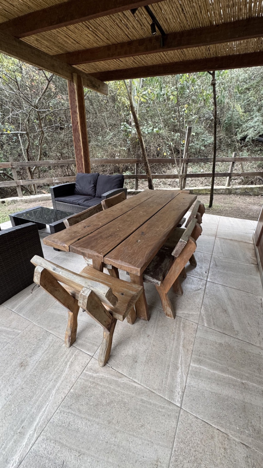 Terraza cubierta con mesa de madera y vista al bosque